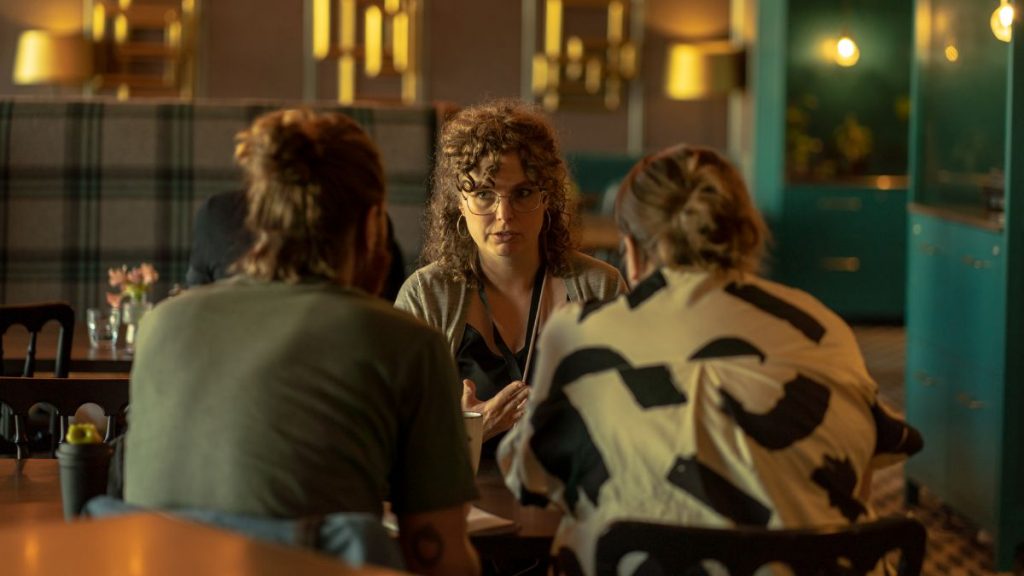 A women having a meeting with 2 people at a table in a restaurant 